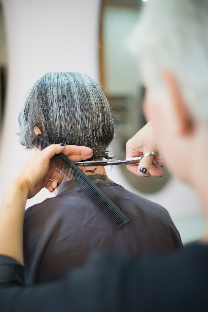 A hairstylist skillfully cutting a woman's hair with scissors and comb indoors.