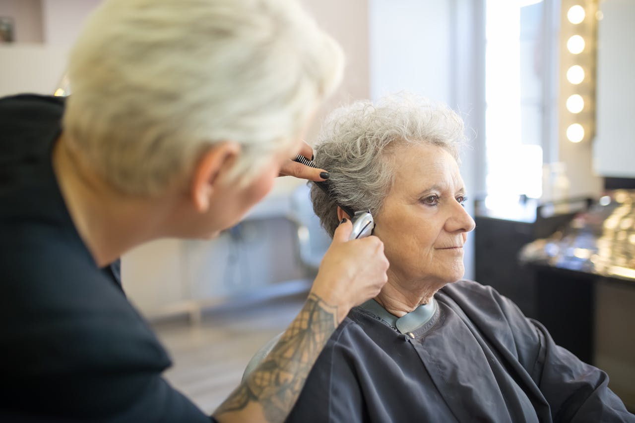 services-08 An elderly woman receiving a haircut from a skilled stylist in a contemporary salon.